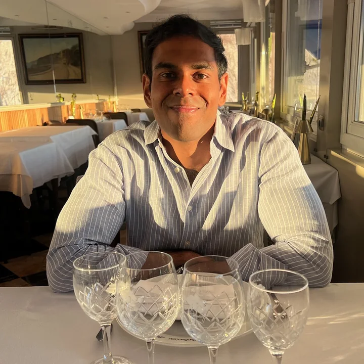 Hans Muneesamy at a restaurant table set with wine glasses